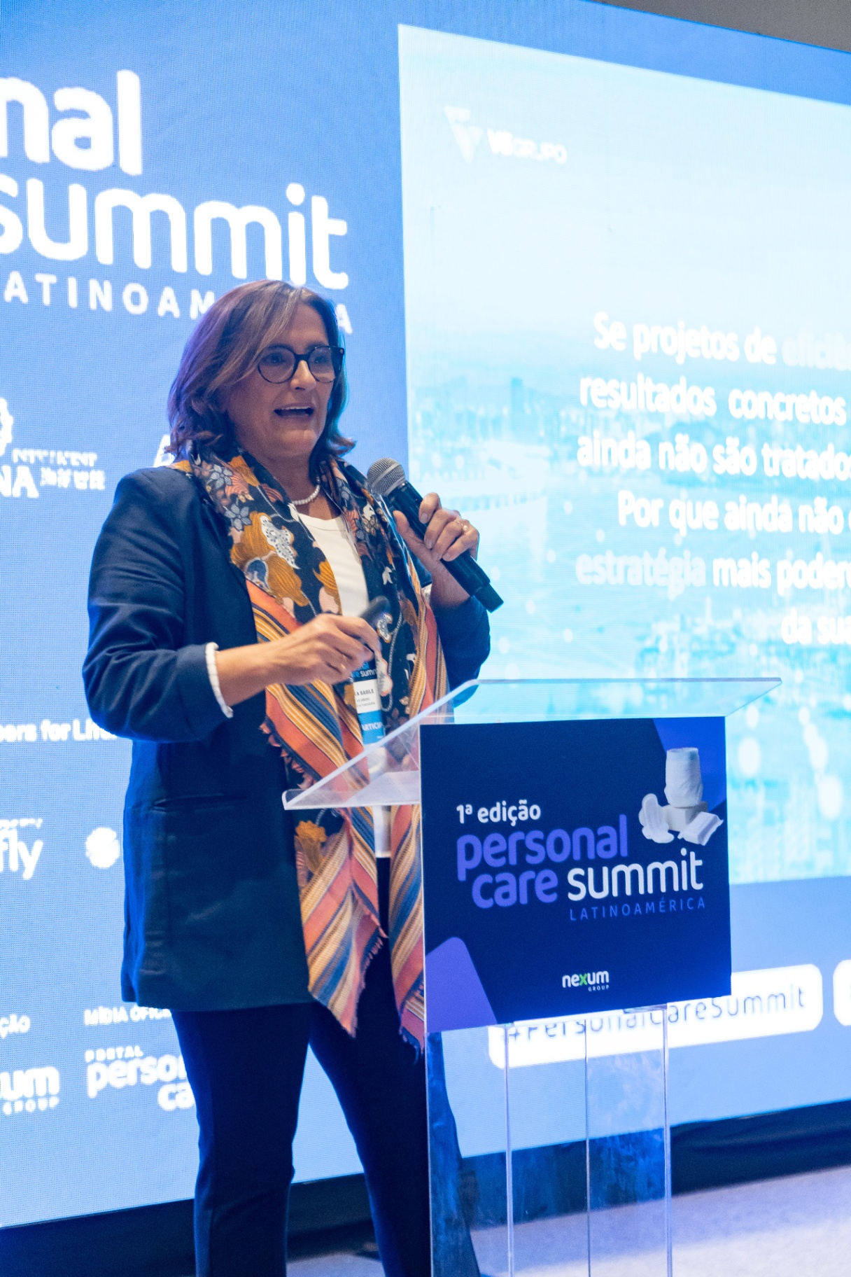 Palestrante no palco com público durante apresentação